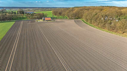 Fototapeta premium Aerial drone view of plowed agricultural field ready for planting, rows of soil agriculture background