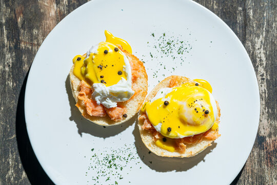 Egg benedict or poached egg with salmon on white plate. Isolated by wooden background or table. Food photography