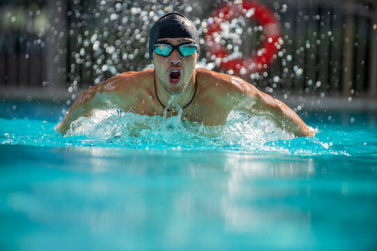 Professional man swimmer swims in an outdoor pool. Young man swimming in pool in butterfly style. Young adult professional swimmer athlete conducts a training session. Healthy lifestyle  concept.