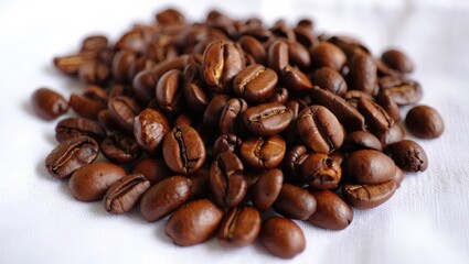 Fototapeta premium A pile of coffee beans on a white surface.