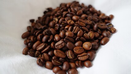 Naklejka premium A pile of coffee beans on a white surface.