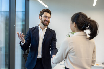 Fototapeta na wymiar A business professional is shaking hands with a colleague in a modern office setting. This portrays a collaborative work environment.