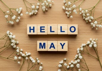 Hello may message spelled out with wooden blocks surrounded by baby's breath flowers on wood surface