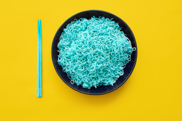 Bright blue noodles with chopsticks on yellow background