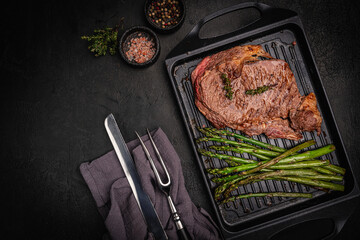 Beef grill steak with green asparagus on a grill pan. Healthy dinner or lunch, top view. High quality photo