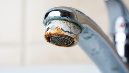 Close-up view of a water faucet showing significant mineral deposits and rust accumulation, indicating a need for cleaning and maintenance in a home bathroom environment