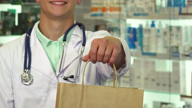 Doctor smiling and holding a package in drugstore