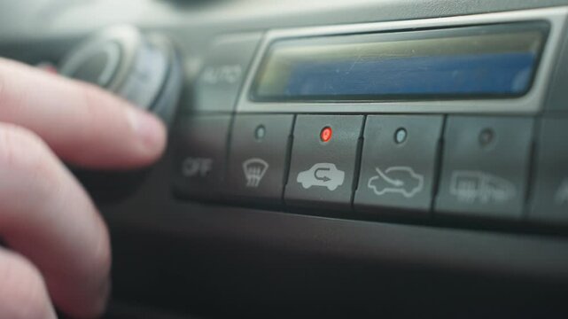 close up hand pressing ac button on car climate control panel with red indicator light and subtle lens flare adding authentic realism to cabin comfort scene interior in sunlit morning drive