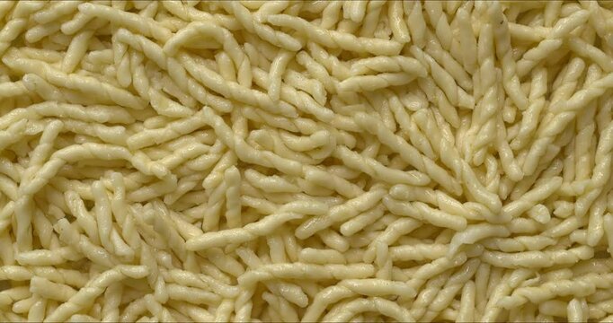 Cooked trofie pasta background texture. In Ligurian cuisine, trofie is most typically served with a pesto sauce. Table spin. 