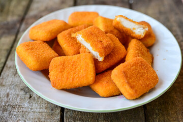 White cheese nuggets on wooden background. Vegetarian  cheese  breaded oven baked  snack