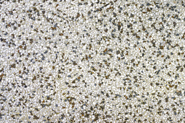 A mottled, light background of small, colorful stone chips embedded in a gray cement base