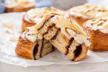 Cinnamon rolls cut in half topped with cream cheese frosting and sliced almonds