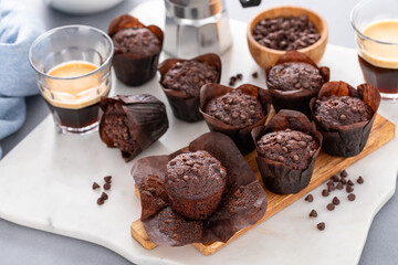 Chocolate chip muffins on a board served with milk with one muffin unwrapped