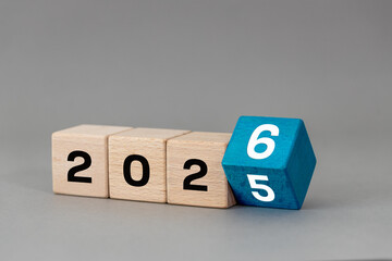 2026. Change the year 2025 to 2026. Wooden blocks with a changing date. Grey background. Symbol New...