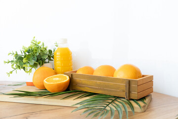 Fresh oranges and juice bottle on wood table with green plant and palm leaf in front of yellow backdrop Flatlay with oranges and juice bottle on wooden surface and white background with tropical palm