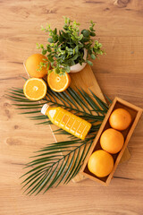 Fresh oranges with juice bottle on wooden table decorated with palm leaves, combining tropical freshness, healthy lifestyle and natural vitamin rich citrus beverage concept