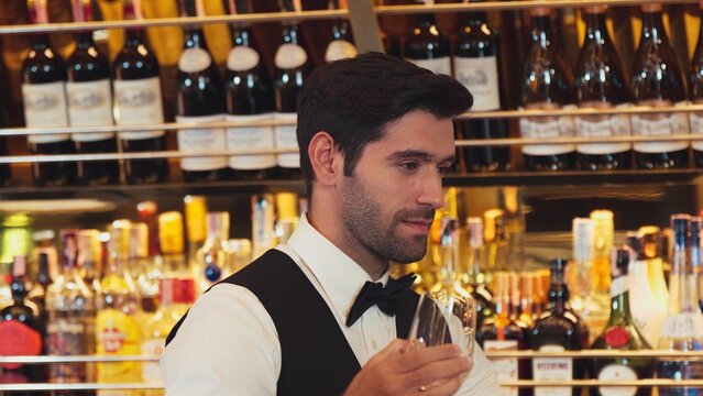 Good looking bartender chilling glass with ice for serving customer at beverage bar counter of welcome drink with charm professionalism, making great first impression warm smiling greeting. Vinosity.