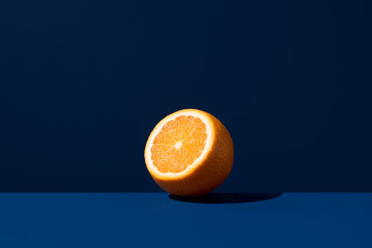 Fresh orange half on deep blue background with shadow