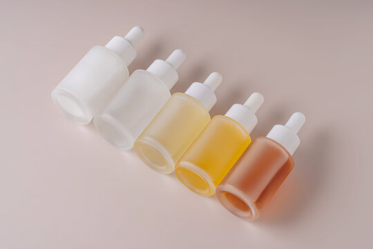 Gradient collection of dropper bottles on a beige background