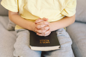 A boy is reading the holy bible and praying or meditating. Concept of Christianity, religion and...