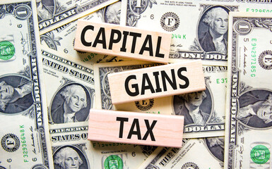 Capital gains tax symbol. Concept words Capital gains tax on beautiful wooden blocks. Dollar bills. Beautiful background from dollar bills. Business and capital gains tax concept. Copy space.