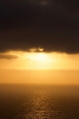 Beautiful ethereal sunset with moody clouds and orange yellow light over calm ocean in San Diego, California