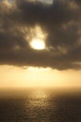 Beautiful ethereal sunset with moody clouds and orange yellow light over calm ocean in San Diego, California