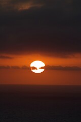 Beautiful pink orange sunset with clouds blocking part of the sun, moody clouds, over ocean in san diego california