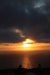 Beautiful ethereal sunset with moody clouds and orange yellow light over calm ocean in San Diego, California