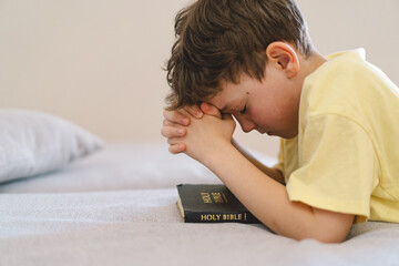 Obraz premium A boy with folded hands in front of him, he is praying or meditating. Concept of Christianity, religion and faith.