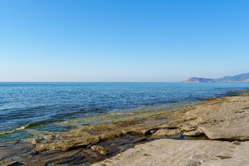 Rocky Seashore with Calm Waters under Clear Blue Sky on a Sunny Day..