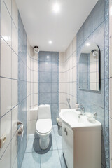 Compact bathroom with white toilet and sink, ceramic tile walls, and a well-organized layout.