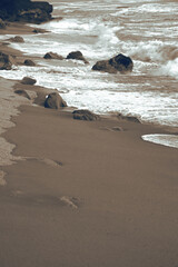 Seascape. Wild beach of Portugal. Waves in motion. Stones washed by water. Abstract background with space for insertion. Wallpaper. Postcard. Poster