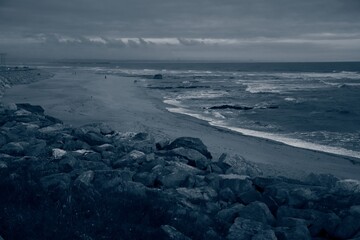 Seascape. Wild beach of Portugal. Waves in motion. Stones washed by water. Abstract background with space for insertion. Wallpaper. Postcard. Poster