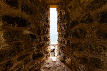 Narrow View Through an Ancient Stone Wall Corridor to the Sea Beyond..