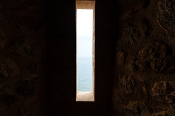 Dimly lit ancient stone corridor with light streaming through an open door, evoking mystery and...