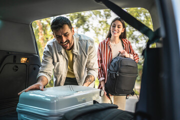 man and women couple pack luggage baggage in trunk of the car