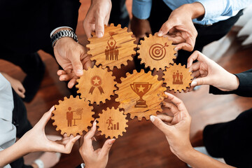 A creative representation of teamwork showing hands holding wooden gears with symbols of success...
