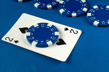 Two of spades card sits on top of a blue poker chip, surrounded by more chips on a blue surface, capturing the essence of a lively night of card games with friends