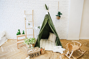 Cozy indoor play area with a green teepee and decorative elements for children © ir1ska