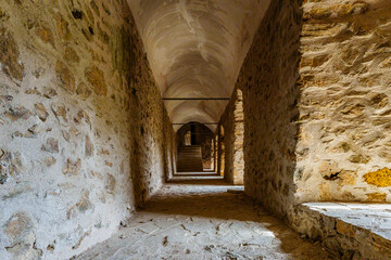 Historic Stone Corridor with Arched Windows and Atmospheric Lighting..
