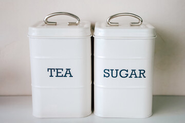 Storage containers for tea and sugar placed on a kitchen counter
