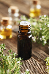 A dark bottle of thyme essential oil on a wooden background
