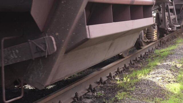 Close-up of freight train rolling stock. Low-angle close-up of steel freight car wheels rattling on concrete sleepers. Loaded hopper cars moving. High quality 4k footage