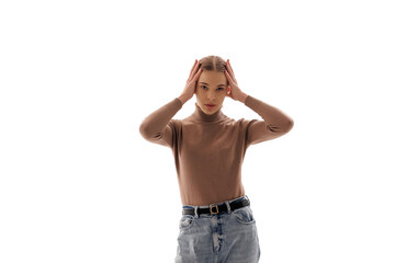 Young woman expressing emotion with hands on her head in a studio setting during a light background