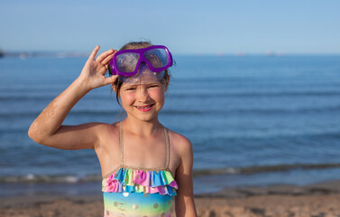 Young girl enjoying beach day with snorkeling goggles by the sea