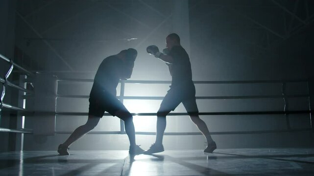 Boxers sparring in dark gym with blue backlight