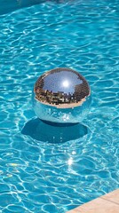 Shimmering disco ball on poolside with clear water reflection