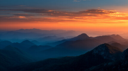 Orange sunset over layered blue mountains, creating a scenic landscape, showcasing tranquility and natural beauty, ideal for travel or nature concepts