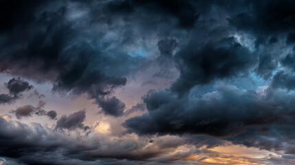 Obraz premium Dramatic sky image showcasing dark, textured clouds with hints of orange and purple hues at the horizon, creating a moody atmospheric scene perfect for background use